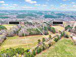 Aerial view of two rectangular, wooded and grassy properties outlined in white, labeled "6150 Bob Daniel Rd" and "6142 Bob Daniel Rd," set among trees and fields with a road visible on the right.