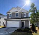 A two-story modern gray house with white trim at 30 Gerrard Street, Franklinton. It features a double garage, dark front door, and a small front yard. The sun shines brightly above as a tree stands to the right of the house.