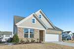 A modern two-story suburban house at 124 Tillamook Lane in Franklinton, featuring brick and siding exterior, white trim, a two-car garage, minimal landscaping in the front yard, and a clear blue sky above.