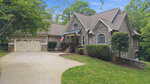 A suburban house in Youngsville at 1001 Browning Place, featuring a stone and siding exterior, gabled roof, attached two-car garage, American flag by the front porch, lush trees and shrubs, and a curved concrete driveway.