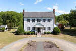 A large, white, two-story colonial-style house at 3679 Oak Lawn Farm Road, Oxford, features black shutters, brick chimneys, a covered front porch, and is surrounded by neatly trimmed bushes, trees, and a circular gravel driveway.