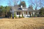 A single-story white house on 815 N Durham Avenue in Creedmoor features a front porch, wooden shutters, and a gray roof, all surrounded by trees and a large, dry grass yard on a sunny day.