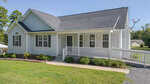 Charming single-story white house at 2514 Wes Sandling Road, Franklinton, with gray roof, front porch, and wheelchair-accessible ramp. Grassy yard features small shrubs; satellite dish on the roof. Trees and another house visible in the background.