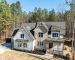 Located at 1226 Red Cedar Court in Youngsville, this two-story modern farmhouse-style home features brick and white siding, large front windows, a covered porch, and a sloped driveway, surrounded by tall pine trees and a dry lawn.