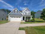 Two-story modern suburban house at 300 Olde Liberty Drive, Youngsville, with gray siding, white trim, a double garage, and a covered front porch on a spacious lawn, surrounded by neighboring homes under a blue sky.