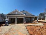 Located at 17 Bee Balm Court in Youngsville, this newly constructed two-story house features stone accents, a double garage, and a covered front porch. The yard and driveway remain unfinished with exposed red dirt and visible construction materials.