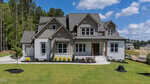A modern two-story house at 55 Broadleaf Lane in Youngsville with gray siding, white trim, and a covered front porch. The home is surrounded by green lawn, young plants, and trees under a blue sky with clouds.