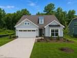 A modern, single-story house at 170 Sawtooth Oak Lane in Youngsville features light blue siding, a dark shingle roof, and a two-car garage, surrounded by green lawn and young trees against tall trees and blue sky.