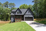 A modern gray house with black trim at 212 Rawhide Drive in Louisburg features a covered front porch and attached two-car garage, set on a well-manicured, sloping lawn surrounded by tall trees under a clear blue sky.