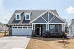 A gray two-story house with white trim, a covered front porch, double garage, and gabled roof sits on a freshly landscaped yard with a concrete driveway under a partly cloudy sky at 40 Slippery Elm Road in Youngsville.