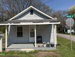 Charming small gray house at 631 Marshall Street, Henderson, featuring a covered front porch, white trim, potted plants, and a light gray mailbox. A "Marshall St" sign stands nearby with trees and another house in the background.