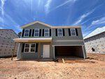 A newly constructed two-story house at 160 Sugarmaple Way in Youngsville features gray siding, black shutters, a covered front porch, and a spacious two-car garage on a bare dirt lot under a blue sky.