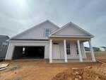 A newly constructed single-story house at 69 Moon Flower Walk in Youngsville, featuring gray siding, white trim, a covered front porch, and an unfinished front yard. The open garage door reveals the bare interior.