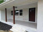 A front porch at 194 Furney Pearce Road in Zebulon features a white painted brick exterior, dark brown columns, a maroon front door with black door hardware, a white ceiling, and a small outdoor light fixture. Black mulch borders the edge of the porch.