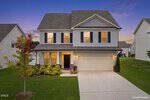 Charming two-story suburban home at 475 Hawksbill Drive, Franklinton, with gray siding, black shutters, a welcoming front porch, and attached two-car garage. Manicured lawn and sunset skies create a warm, inviting atmosphere.
