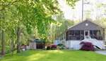 Nestled on 101 Bow Drive in Louisburg, this cozy house features a large screened porch, lush green trees, and a well-kept lawn. A charming gazebo and vibrant flowering bushes complete the sunlit yard.