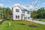 Two-story modern house at 102 Airdale Drive, Oxford, with a white exterior, large windows, and dark trim, surrounded by a green lawn, young trees, and a clear driveway on a sunny day with blue sky.