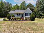 Charming single-story home at 2137 Sterling Creek Lane, Franklinton, with a front porch, white railings, and dark shutters. Surrounded by shrubs and trees, it sits on a spacious grassy lawn beneath a partly cloudy sky.