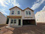 A two-story house under construction at 45 Plantation Drive, Youngsville, wrapped in insulation material with exposed wooden framing and an unfinished garage. The ground is bare soil and other homes are being built nearby under a partly cloudy sky.