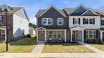 Two-story duplex at 712 Winton Way, Wake Forest, features brick and dark gray siding, white trim, and a covered porch. Sidewalk leads to the entrance with a small lawn and minimal landscaping under a clear blue sky.