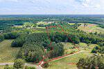 Aerial view of a wooded and partially cleared rural property at 360 J B Leonard Road, Castalia, outlined in red; surrounded by trees, fields, and a few scattered buildings under a blue, cloudy sky.