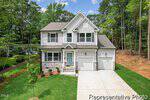 Charming two-story house at 165 Oswego Drive, Louisburg, with gray siding, stone accents, a light blue front door, and double garage. Enjoy a lush green lawn, trees, and wooded scenery under a blue sky with clouds.