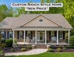 A brick ranch-style house at 120 Georgetown Woods Drive, Youngsville, features white trim, columns, rocking chairs on the porch, a wreath on the door, and green trees in the background. Overlaid text reads: "Custom Ranch Style Home *New Price*".