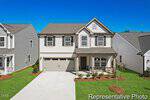 Charming two-story suburban house at 113 Ute Lane in Louisburg with gray siding, a double garage, and a covered front porch. The yard features fresh green grass and young landscaping under a bright blue sky.