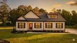 A modern farmhouse-style home at 35 Autumnwood Lane, Zebulon, with white siding, black trim, and a red front door sits amid a well-kept lawn and trees in the background, beautifully photographed at sunset.