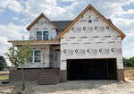 A two-story house under construction at 45 Diamond Creek Drive, Zebulon, is covered in white weatherproof wrap with logos, featuring a front porch, brick steps, double garage, and a small tree in the sandy yard under a partly cloudy sky.