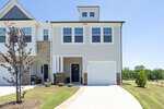This modern two-story townhouse on 247 Blandford Street in Franklinton features light gray siding, white trim, and a single-car garage. A small tree and neat landscaping adorn the front yard beneath a clear blue sky.