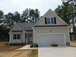 A modern two-story beige house at 35 Copper Penny Road in Zebulon, featuring a double garage, white trim, and a covered front porch. The front yard has dry grass and pine trees in the background.