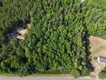 Aerial view of a dense, forested area in Rougemont, bordered by a road at the bottom near 1401 Black Farm Road. Two buildings are partially visible on the left and right edges, while trees cover most of the central area.