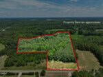 Aerial view of a wooded property outlined in red at 00 Mt Pleasant Church Road, Manson, showing approximate property lines surrounded by forest, fields, and a nearby road under a partly cloudy sky.