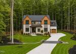 Modern two-story house at 290 Hidden Lake Drive in Youngsville, featuring wood and stone accents, large windows, and an attached garage. Surrounded by a manicured lawn and tall trees with a curved driveway leading to the entrance.