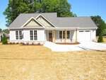 This single-story house at 302 S Elm Street in Creedmoor features light-colored siding, multiple front windows, a covered entryway with wooden posts, and an attached single-car garage on a lot with fresh straw and minimal landscaping.