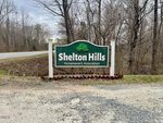 A green and white sign reading "Shelton Hills Homeowners Association" stands by a rural road near Oxford, with bare trees and patchy grass in the background. The entrance is close to 1556 Dogwood Drive.