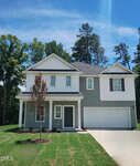 Modern two-story house at 101 Airdale Drive, Oxford, with gray siding, white trim, and a double garage. A small tree accents the front yard with green grass and a concrete driveway. Tall trees line the background under a blue sky.