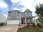 Charming two-story suburban house at 169 Sugarmaple Way in Youngsville, featuring gray siding, white trim, a covered front porch, double garage, landscaped front yard, and a partly cloudy sky overhead.