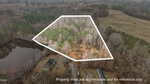 Aerial view of a wooded property at 120 Corinth Drive, Louisburg, outlined in white, showing dense trees, a nearby pond, open field, and several buildings. Text reads: "Property lines are approximate and for reference only.