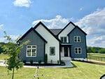 A modern two-story house at 110 Firefly Lane in Youngsville features a black and white exterior, large windows, and a neatly landscaped front yard, sitting under a partly cloudy blue sky surrounded by green grass and trees.