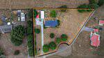 Aerial view of 546 Duke Drive, Rougemont, outlined in yellow, featuring a house with a dark roof, surrounding trees, a driveway, and open grassy areas. Neighboring homes and fields are also visible.