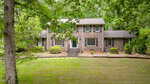 A two-story brick house on 380 Forest Drive in Henderson, featuring white-trimmed windows, a central front door with steps, all surrounded by green lawns, bushes, and tall trees.