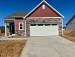 A modern single-story house at 212 Tar Banks Drive in Louisburg features red siding, stone accents, a front porch, and a two-car white garage. The newly constructed driveway and yard have bare soil with no landscaping yet.