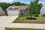 Charming single-story home at 75 Mallory Oak Drive, Franklinton, featuring a two-car garage, stone and siding exterior, small front porch, neatly trimmed shrubs, young tree, plus a concrete driveway and sidewalk leading to the entrance.