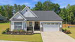 A modern single-story house at 205 Sutherland Drive, Franklinton, with white siding, black trim, stone accents, and a double garage. The home features a manicured lawn, concrete driveway, and is surrounded by trees under a clear blue sky.