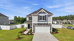 A two-story suburban house with gray siding, stone accents, and a double garage at 675 Hawksbill Drive in Franklinton. It features a well-maintained lawn, white fenced backyard, and sits in a residential neighborhood under a blue sky.