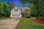 Located at 105 Highview Drive in Youngsville, this two-story white house features a gray roof, front porch, and attached two-car garage with American flags. Surrounded by trees, it has a concrete driveway and landscaped yard at dusk.