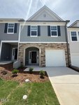 Two-story townhouse at 222 Alberta Drive in Franklinton, featuring gray siding, stone accents, black shutters, a garage, and a small front porch. Enjoy new landscaping with mulch and green grass in the front yard. The driveway leads directly to the garage.