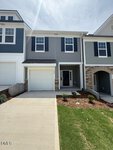 This two-story gray townhouse at 220 Alberta Drive in Franklinton features black shutters, a single-car garage, and a small covered front entry. The freshly landscaped yard boasts green grass and brown mulch, elegantly bordered by neighboring homes.